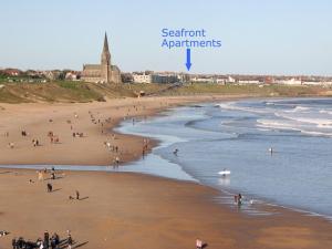 grupa ludzi na plaży blisko wody w obiekcie Seafront Apartments w mieście North Shields