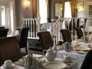 een eetkamer met tafels en stoelen en theeserviezen bij The White Lion Hotel in Wisbech
