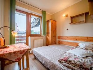 a bedroom with a bed and a table and a window at Dom Wczasowy Stanislawa in Biały Dunajec