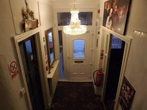 un corridoio con porta bianca e lampadario pendente di Thistle Dhu Guest House a Blackpool