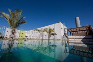 a swimming pool in front of a building with a palm tree at PUMMA BUDGET HOTEL in Canaã dos Carajás