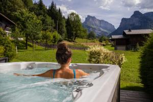 a woman in a hot tub with mountains in the background at Gite Balnéo La Pomme de Pin in Sixt