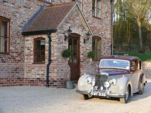 an old car parked in front of a brick building at The Larches Ledbury in Ledbury