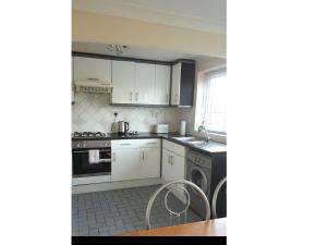 uma cozinha com armários brancos, um lavatório e uma mesa em Thornley Avenue em Billingham