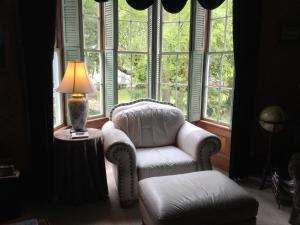 uma sala de estar com uma cadeira, um candeeiro e janelas em Shaw House Inn em Ferndale