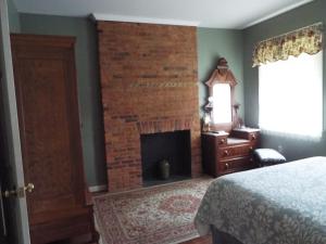 um quarto com uma lareira de tijolos ao lado de uma cama em The Tillie Pierce House Inn em Gettysburg