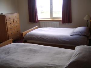 two beds in a hotel room with a window at Top House in Ullapool