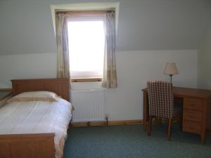 a bedroom with a bed and a desk and a window at Top House in Ullapool