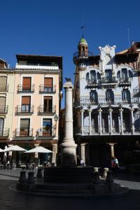 a building with a fountain in front of a building at Apartamentos Plaza del Torico Teruel in Teruel