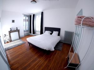 a bedroom with a white bed and wooden floors at La Maison d'hotes de Toucy in Toucy