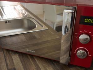 a kitchen with a sink and a red microwave at Townhouse PLUS @ Westminster Street Crewe in Crewe