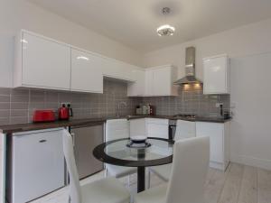 a kitchen with white cabinets and a table and chairs at Townhouse PLUS @ Westminster Street Crewe in Crewe