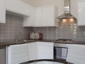 a kitchen with white cabinets and a sink at Townhouse PLUS @ Westminster Street Crewe in Crewe