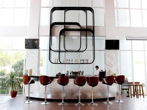 a kitchen with a bar with red bar stools at Hariston Hotel&Suites, Pluit - Jakarta in Jakarta