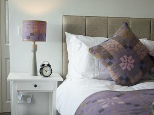 a bed with a clock on a side table with a lamp at The Townhouse in Tenby