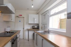 a kitchen with white cabinets and a sink and a window at Budget Rooms @ Underwood Lane Crewe in Crewe