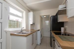 cocina con armarios blancos, fregadero y ventana en Budget Rooms @ Underwood Lane Crewe, en Crewe