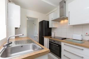 a kitchen with a sink and a black refrigerator at Budget Rooms @ Underwood Lane Crewe in Crewe