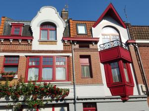 - un bâtiment rouge et blanc avec des fenêtres rouges dans l'établissement Au Troubadour, à Hellemmes-Lille