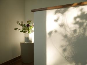 un vase avec des fleurs sur une table à côté d'un mur dans l'établissement Trafohaus am Kaiserbahnhof, à Brühl