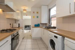 a kitchen with white cabinets and a washer and dryer at Townhouse @ Electricity Street Crewe in Crewe
