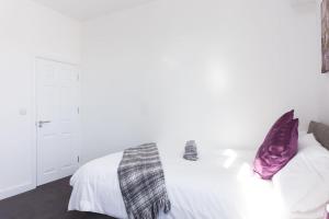 a bedroom with a white bed with purple pillows at Townhouse @ 76 Clare Street Stoke in Stoke on Trent