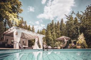 a swimming pool with a white pergola next to a house at Hotel Zur Heimat - Ihr Weidener Hotel mit hauseigenen Parkplätzen und Wellness in Weiden