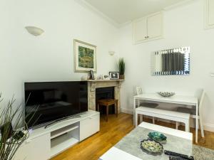 a living room with a large television and a fireplace at Spacious 1 Bed in West Kensington or Hammersmith in London