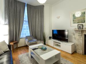 a living room with a couch and a tv and a table at Spacious 1 Bed in West Kensington or Hammersmith in London