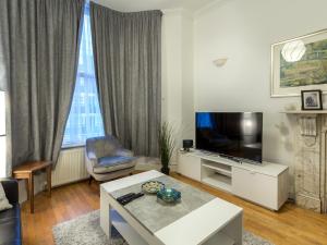 uma sala de estar com uma televisão de ecrã plano e uma mesa em Spacious 1 Bed in West Kensington or Hammersmith em Londres