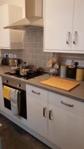 a kitchen with white cabinets and a counter top at Townhouse @ Birches Head Road Stoke in Stoke on Trent