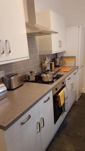 a kitchen with white cabinets and a stove top oven at Townhouse @ Birches Head Road Stoke in Stoke on Trent