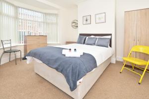 a bedroom with a large bed and a yellow chair at Townhouse @ Earle Street Crewe in Crewe