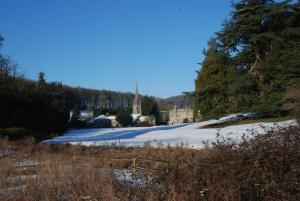 een met sneeuw bedekt veld met een gebouw op de achtergrond bij Garden Studio Spring Cottage in Teffont Magna