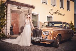 Hotel Zur Heimat في فايدن: عروس تقف بجانب سيارة قديمة