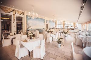 a restaurant with white tables and chairs and a chandelier at Hotel Zur Heimat in Weiden