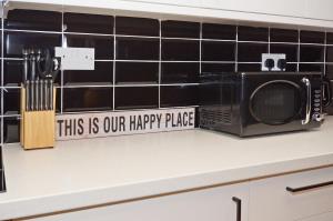 a microwave and a sign that reads this is our happy place at Townhouse PLUS @ 301 West Street Crewe in Crewe