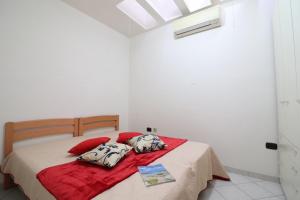 una camera bianca con letto con cuscini rossi di Casa vacanze Arianna in centro a Otranto