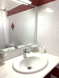 La salle de bains blanche est pourvue d'un lavabo et d'un miroir. dans l'établissement Rodia Studios & Apartments, à Parikia
