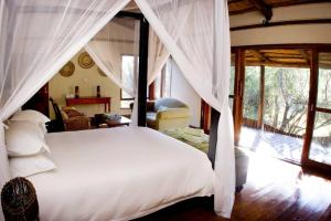 a bedroom with a white bed with a canopy at Ihlozi Bush Lodge in Hluhluwe