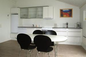 a kitchen with a white table and black chairs at Lyngby Mølle Holiday Apartment in Løkken