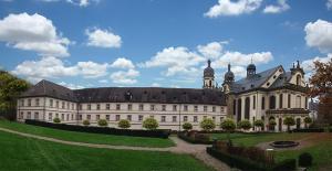 een groot gebouw met een groen gazon ervoor bij Kloster Schöntal in Jagsthausen