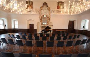 ein leeres Zimmer mit einem Flügel und Stühlen in der Unterkunft Kloster Schöntal in Jagsthausen