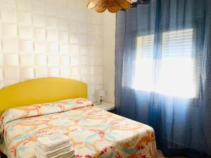 een slaapkamer met een bed en een raam met blauwe gordijnen bij Case La Spiaggia in Sciacca