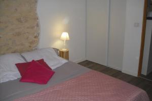 a bedroom with a bed with a red pillow on it at La Lauze lou mas li pitchoun in Gordes