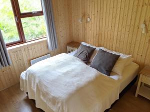um quarto com uma cama com lençóis e travesseiros brancos em Stóra-Vatnshorn em Búðardalur