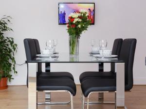 a dining room table with black chairs and a vase of flowers at Sycamore House in Leeds +29 photos