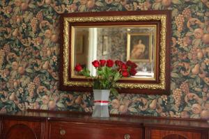 a vase of red roses on a dresser with a mirror at Surfside Inn in Hubbards