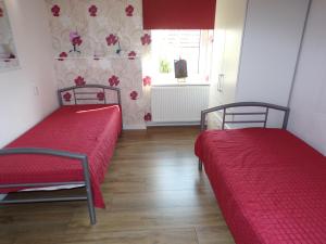 two beds in a room with red sheets and a window at Ferienwohnung am Greifswalder Bodden in Wieck