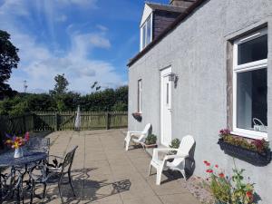 a patio with chairs and a table and a window at West Gallaton Farmhouse in Stonehaven